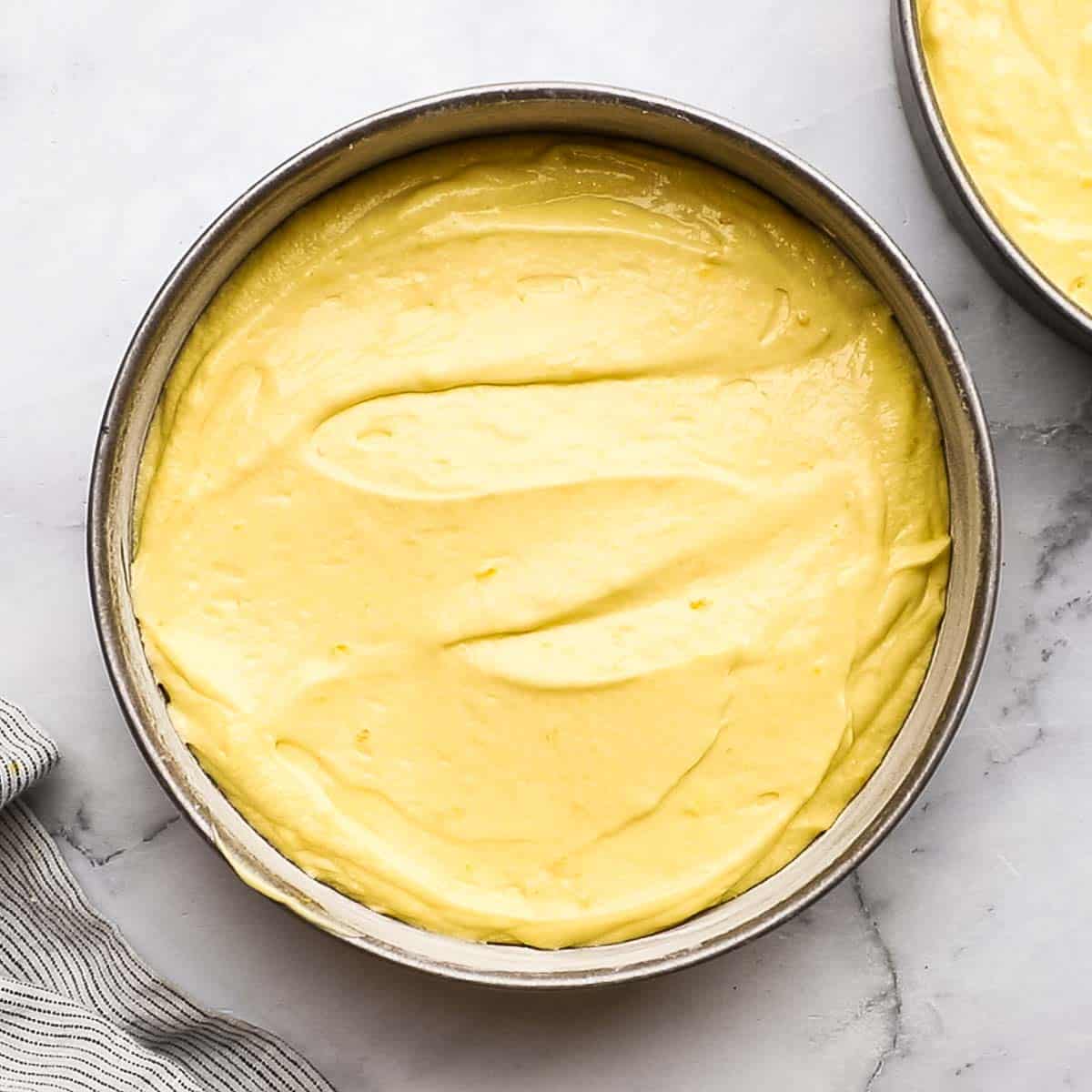 orange cake batter poured in cake pans