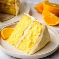 A slice of a two layer orange cake on a plate.