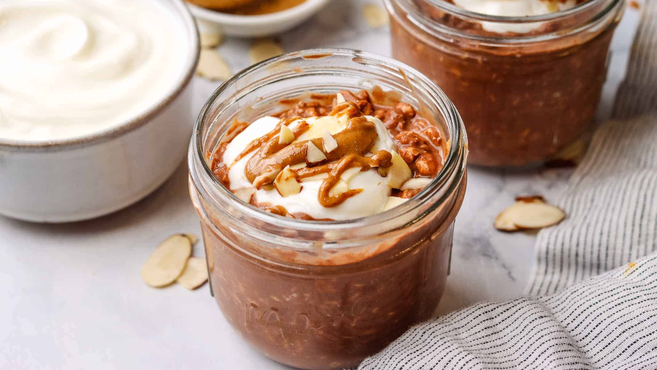 A mason jar of chocolate overnight oats topped with yogurt and almonds.