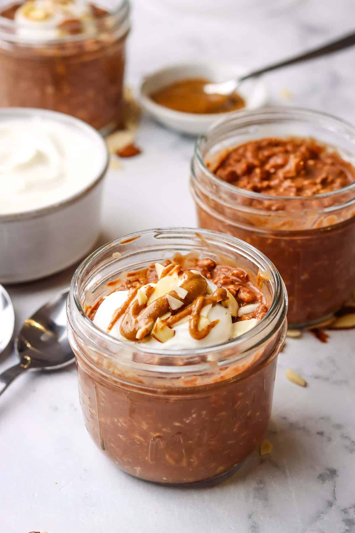 A mason jar of chocolate overnight oats topped with yogurt and almonds.