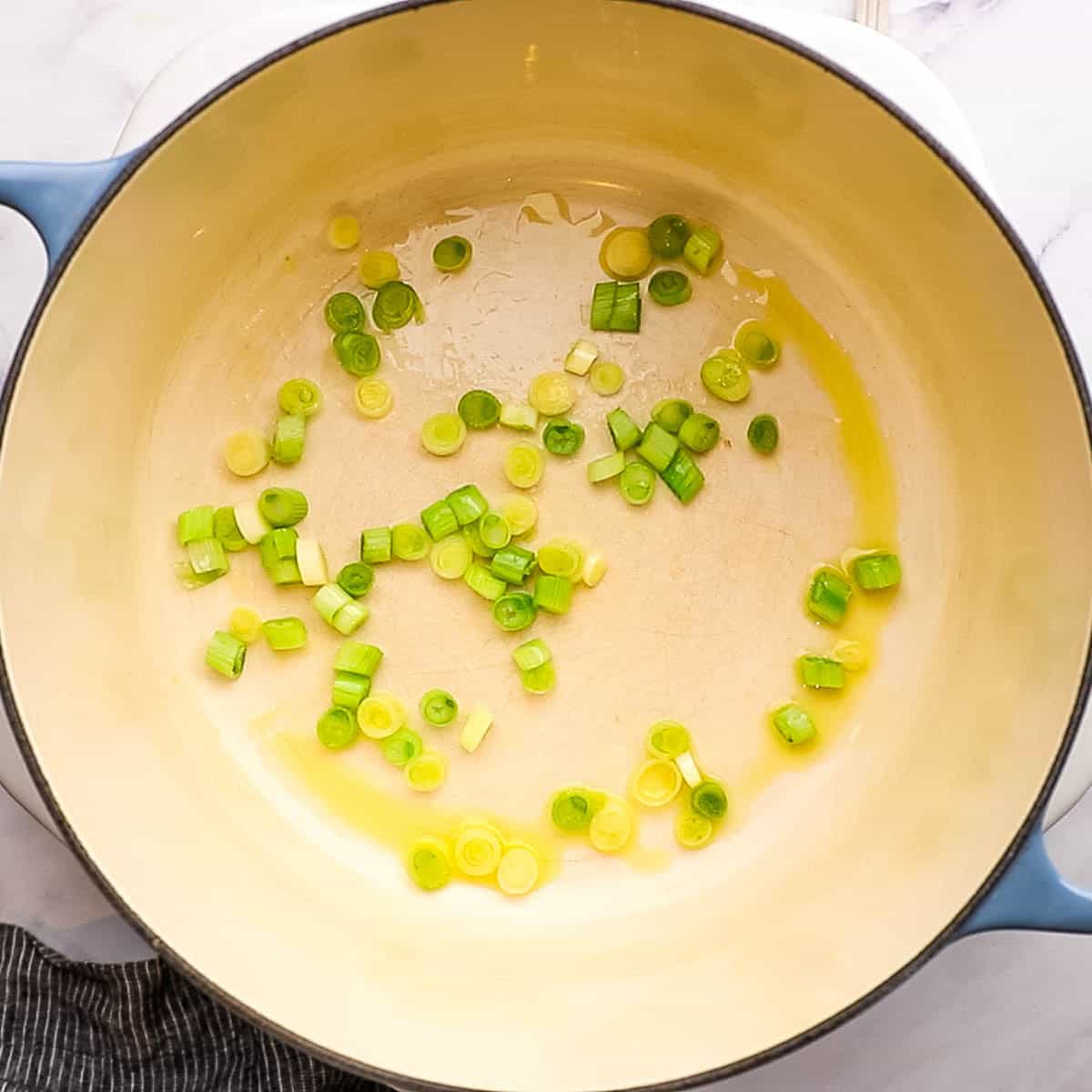 scallion whites and pale greens being sauteed in a large pot