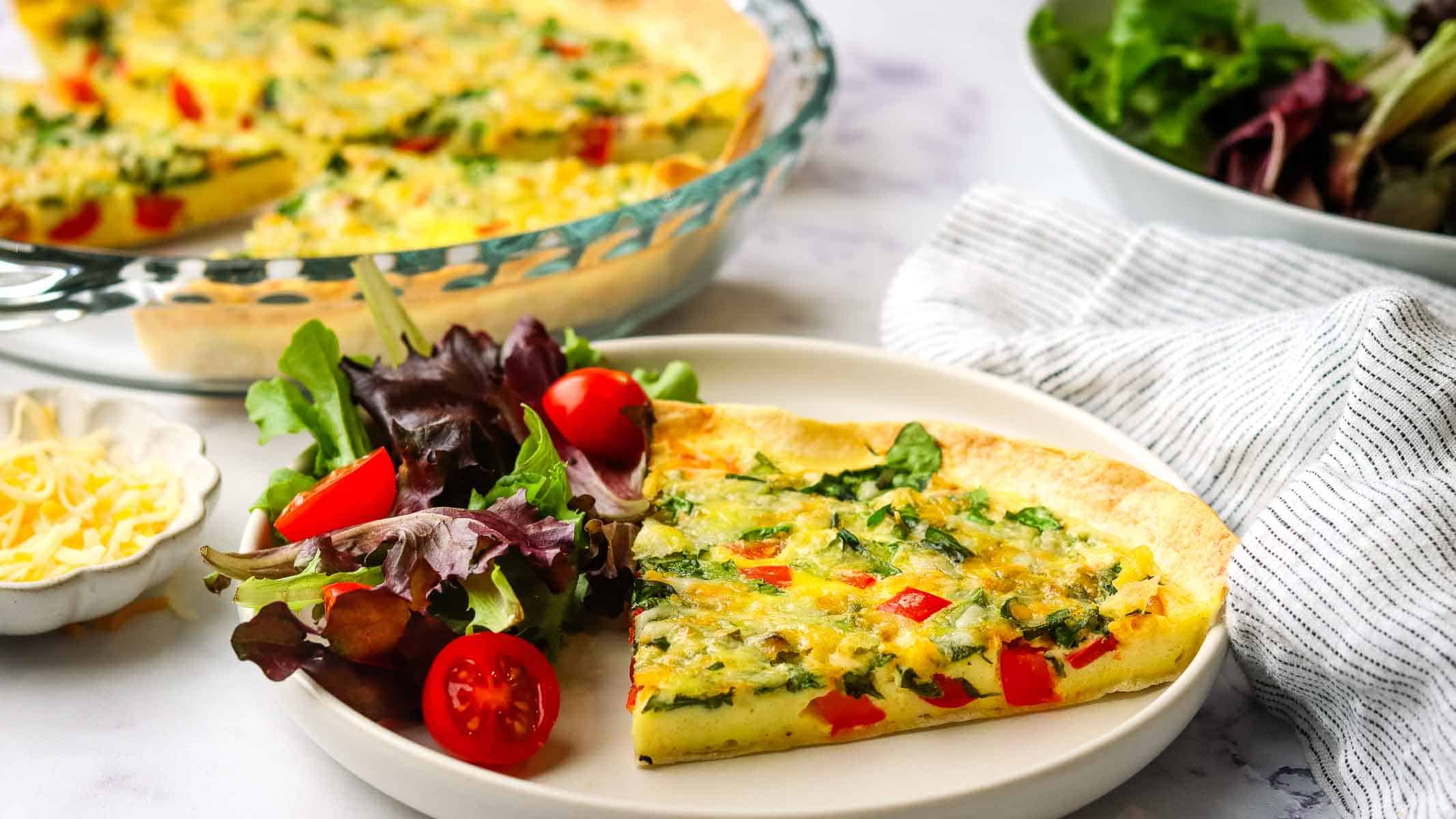 A slice of tortilla quick on a plate with a side salad.