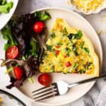 A slice of tortilla quiche on a plate with a side salad.