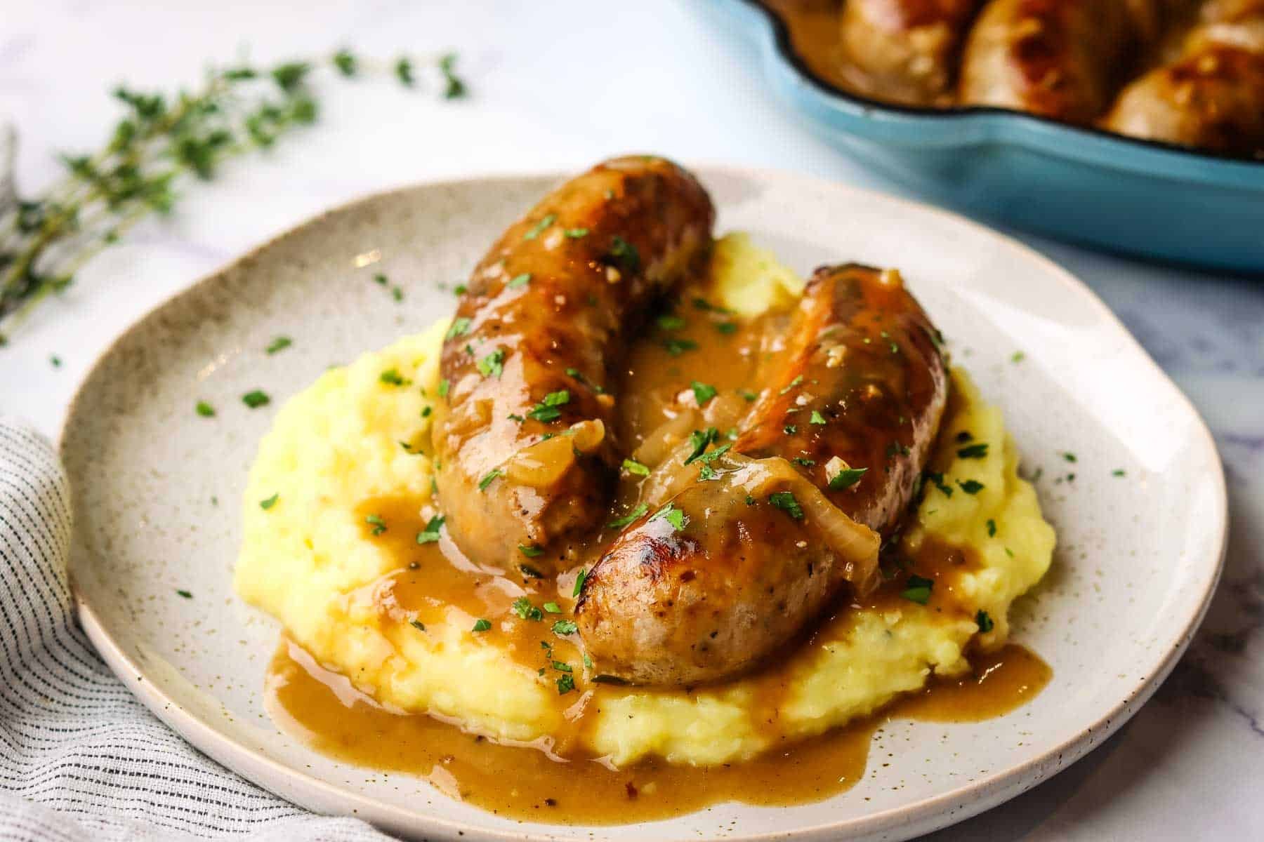 a plate of bangers and mash with gravy on top