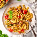 A plate of balsamic pasta salad garnished with basil with a fork in it.