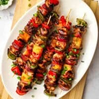 A platter of teriyaki chicken and vegetable skewers.