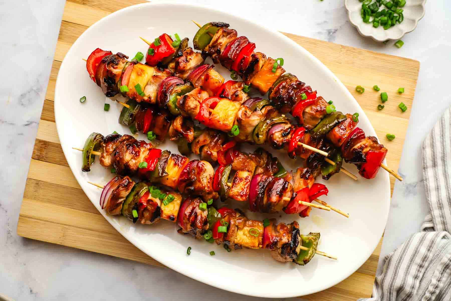 a platter of teriyaki chicken and vegetable skewers.