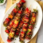 A platter of teriyaki chicken and vegetable skewers.