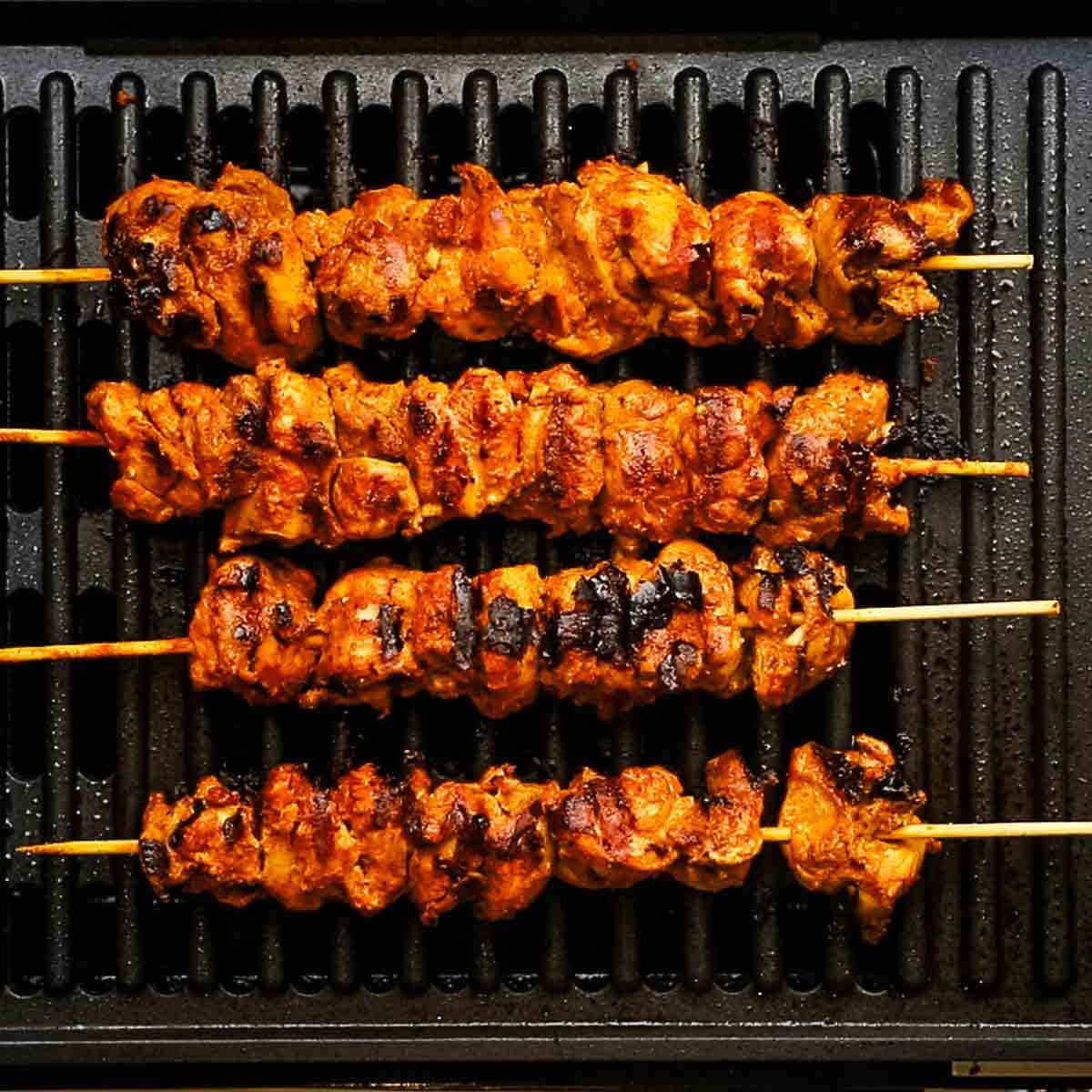 tandoori chicken skewers cooking on the grill