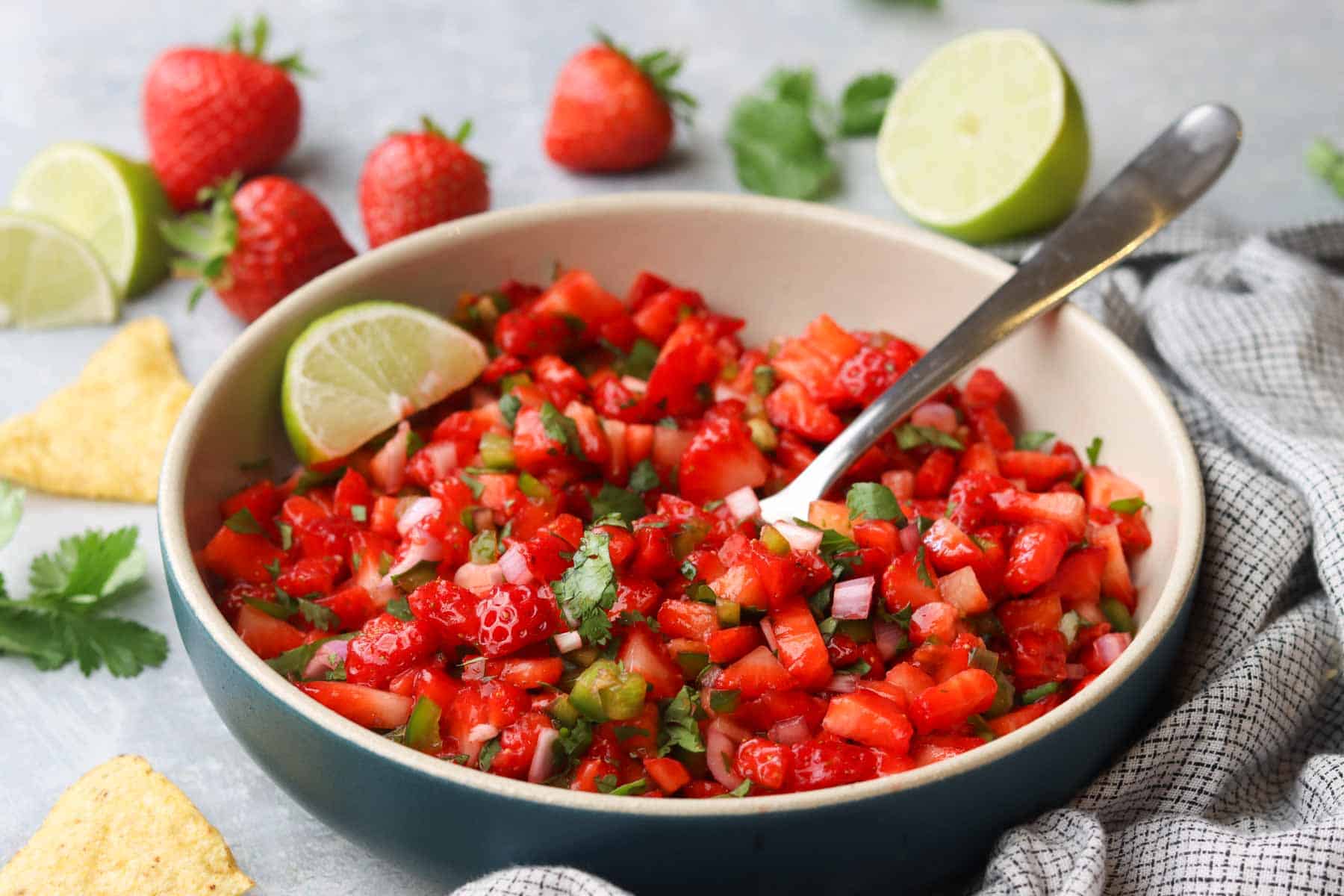 a bowl of strawberry salsa with a spoon in it.