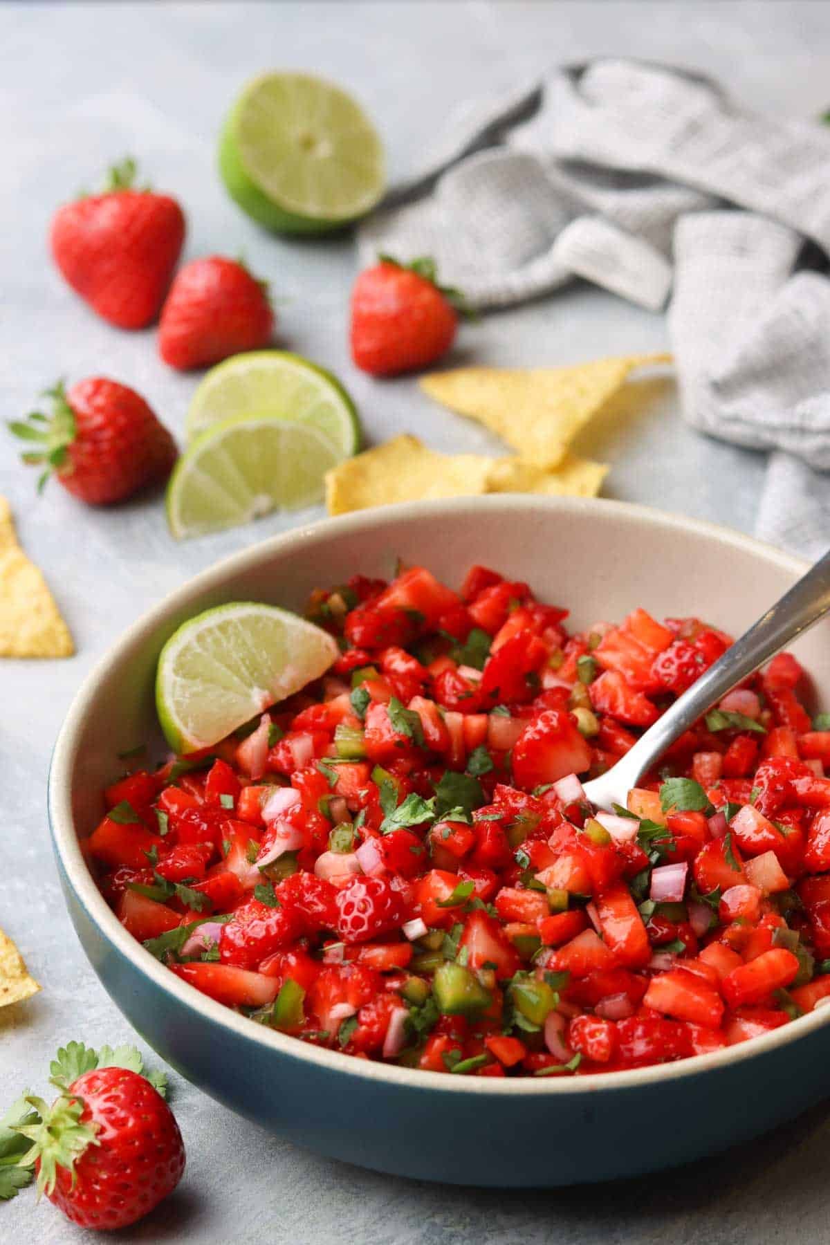 a bowl of fresh strawberry salsa with a spoon in it.