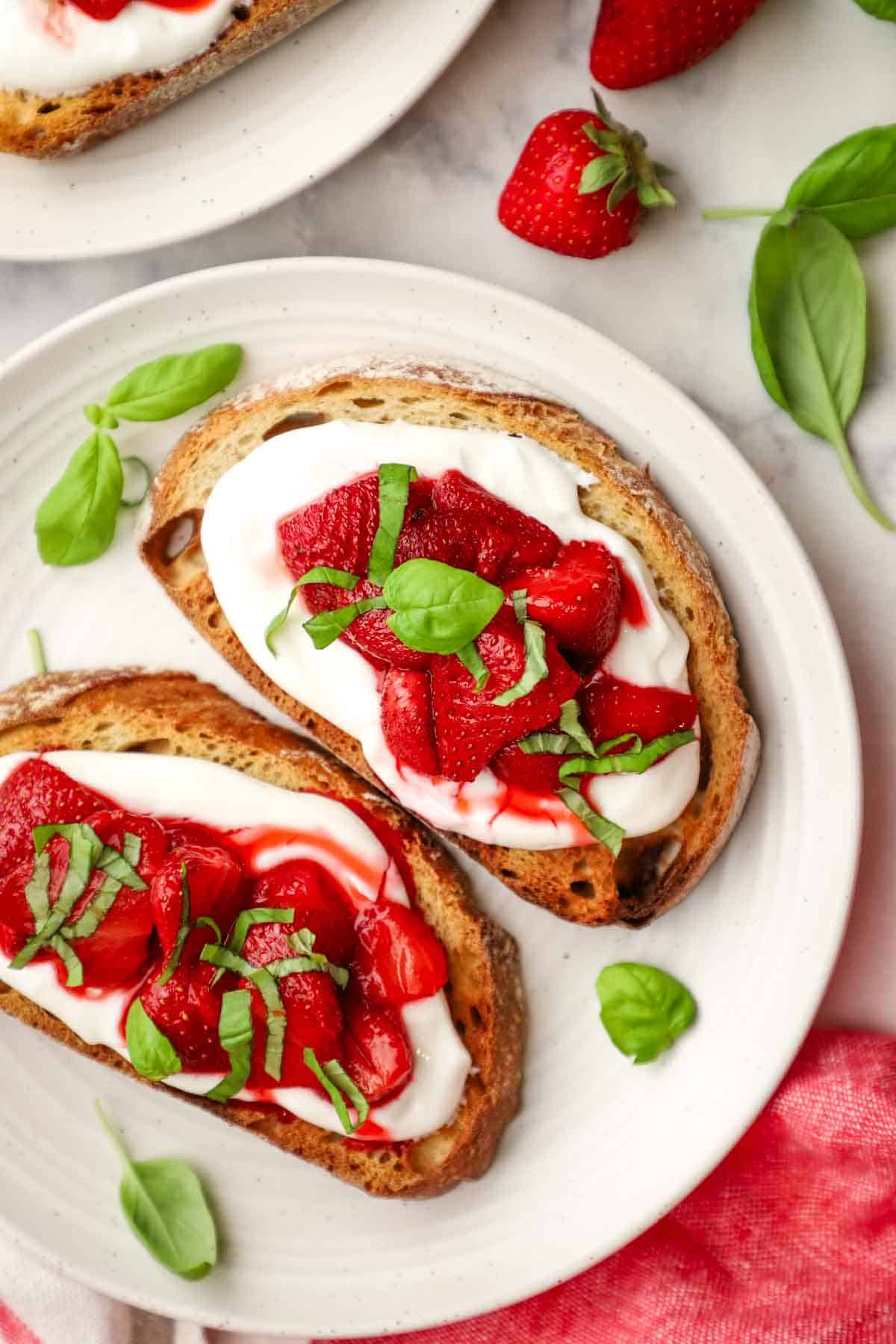 overhead view of a plate of two toasts topped with ricotta and strawberries