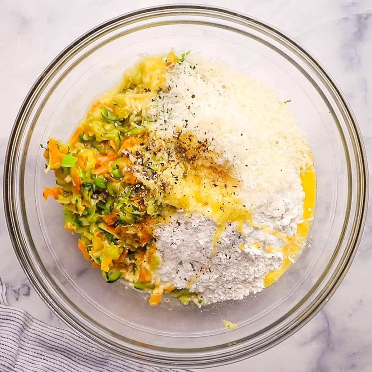 veggies added to a bowl with flour, parmesan, eggs, salt, and pper