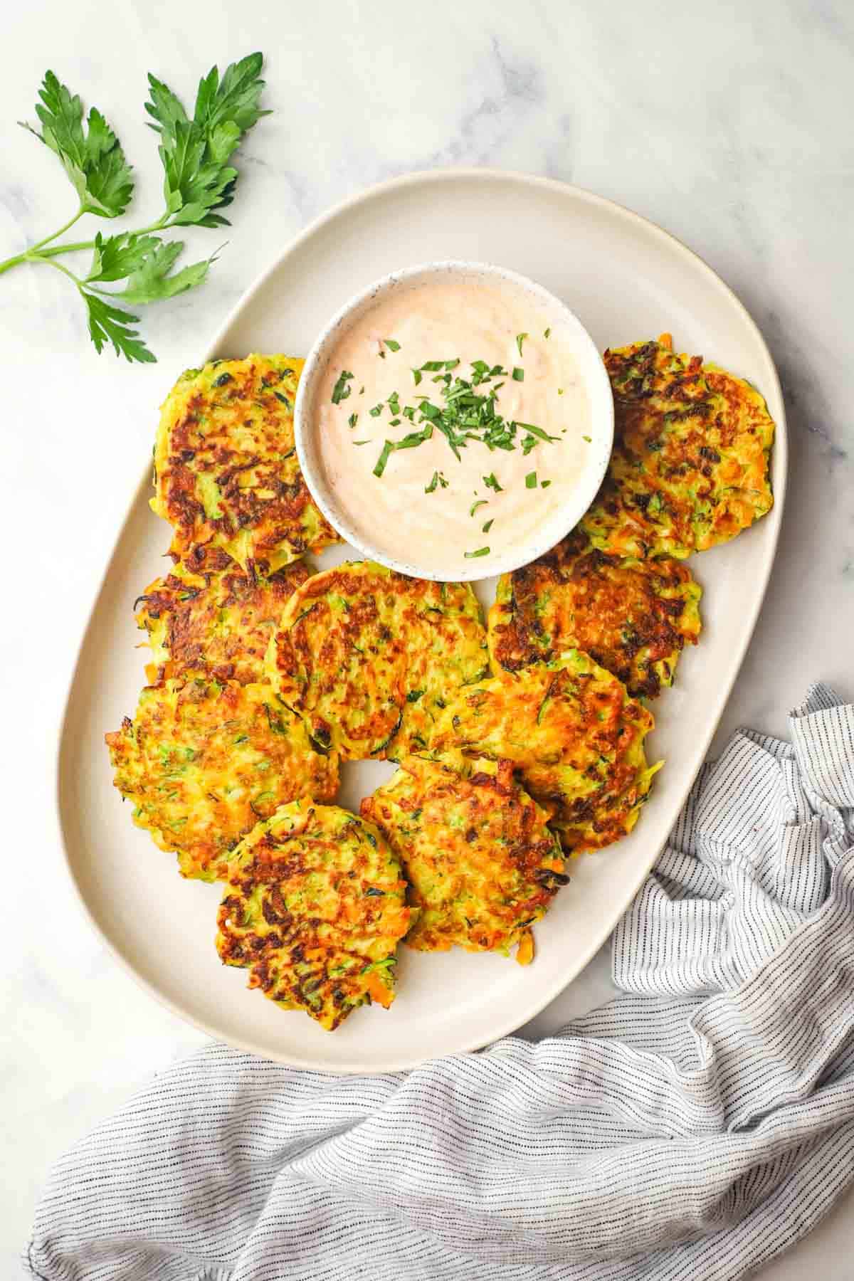 vegetable fritters placed in a serving dish with a dipping sauce