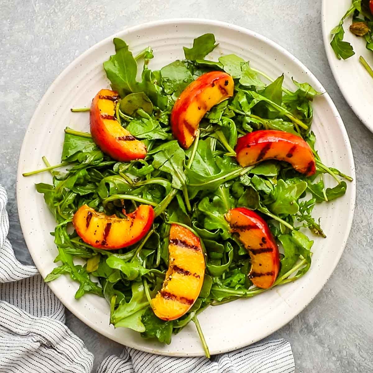 arugula on a plate topped with grilled peaches