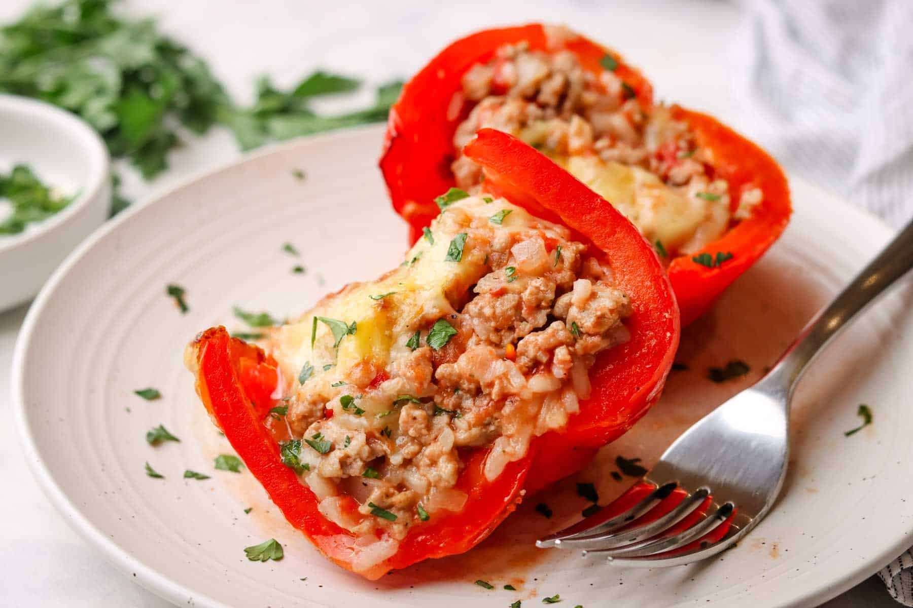 Two halves of a ground turkey stuffed pepper on a plate.