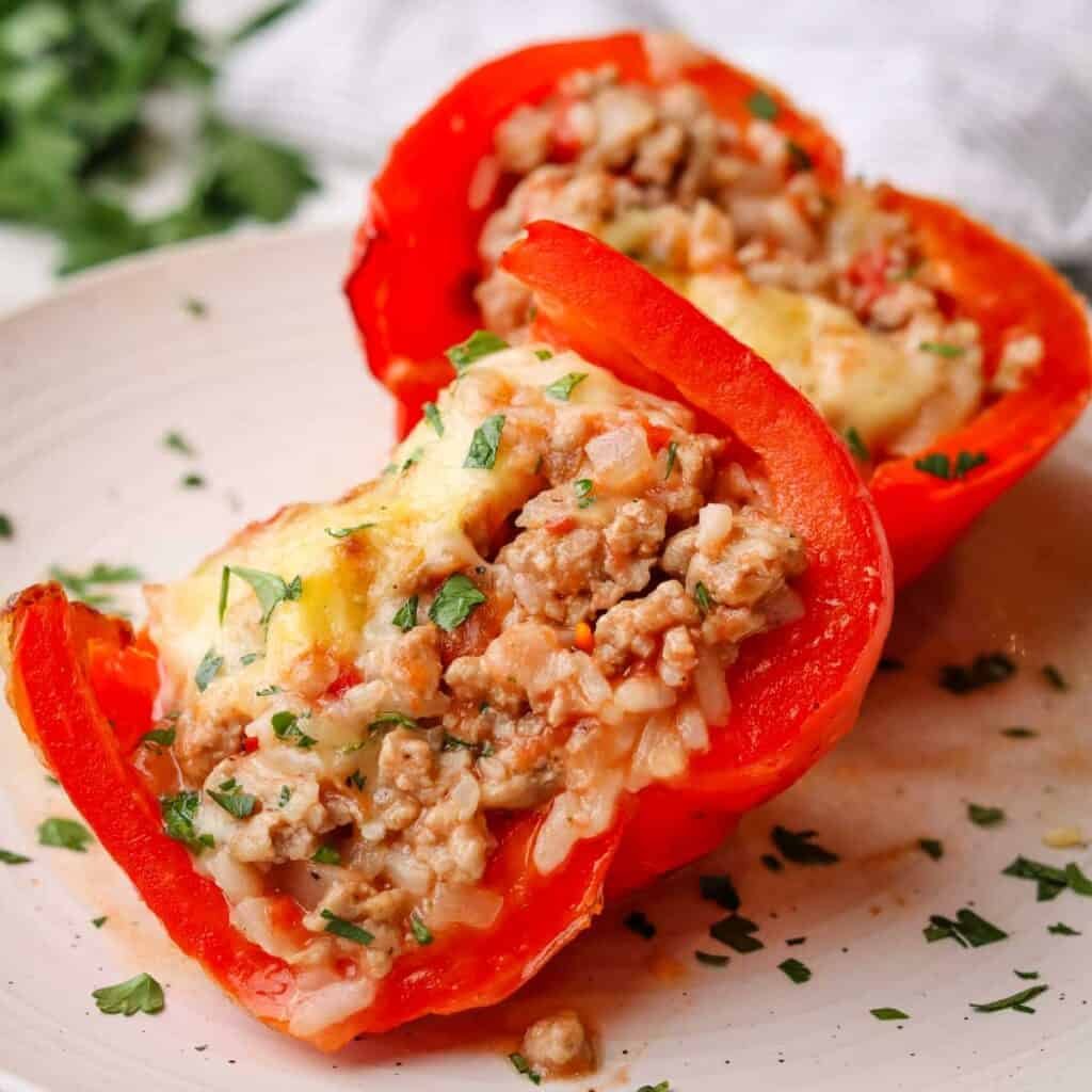 two pieces of red peppers stuffed with a mixture made with cooked ground turkey.