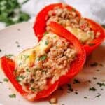 two pieces of red peppers stuffed with a mixture made with cooked ground turkey.