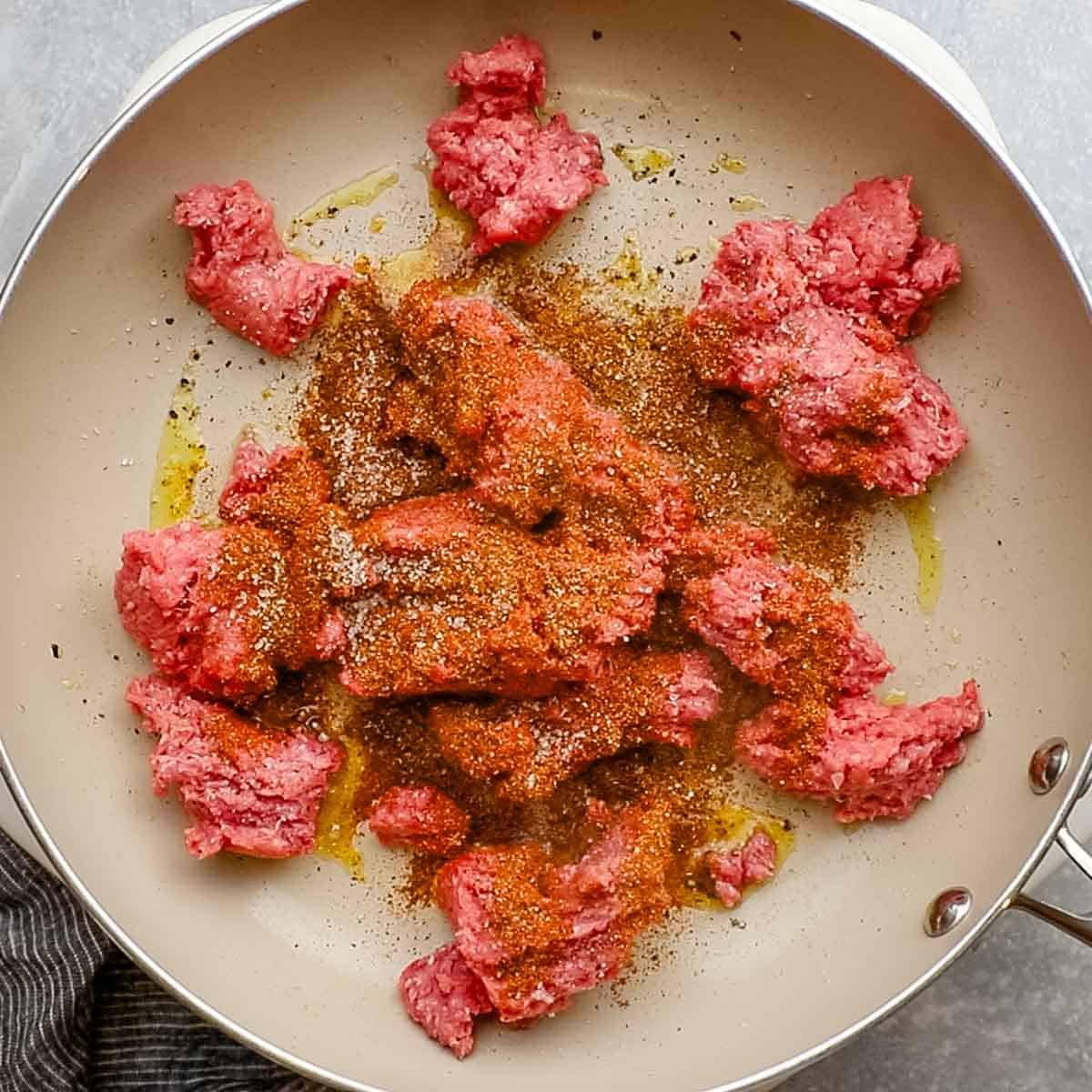 ground beef broken down in a skillet with seasonings added in it
