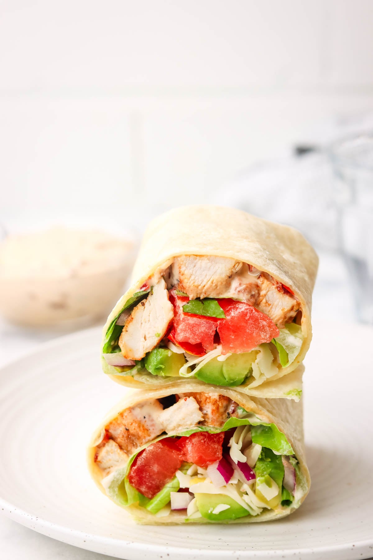 a grilled chicken wrap cut in half and stacked on top of each other on a plate.