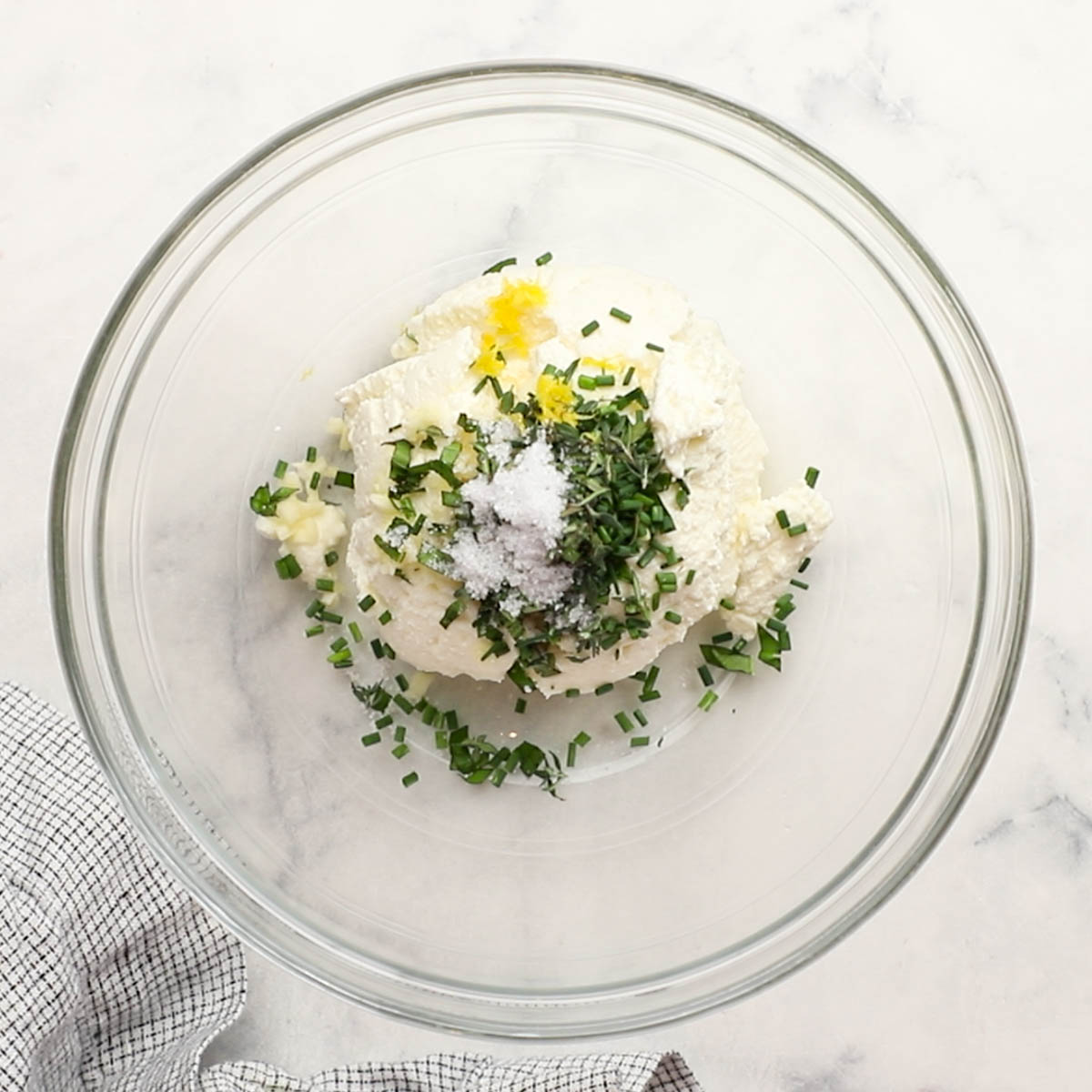 ricotta cheese, herbs, salt, and other things added to a bowl