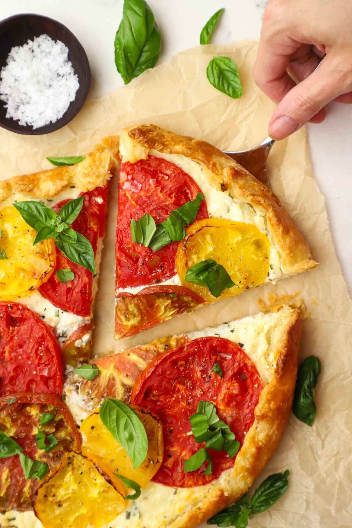 a hand taking out a slice of heirloom tomato tart
