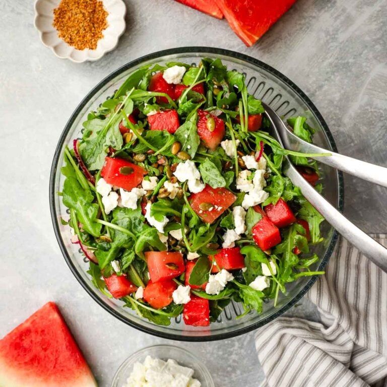 A serving bowl of Mexican watermelon salad with serving utensils.