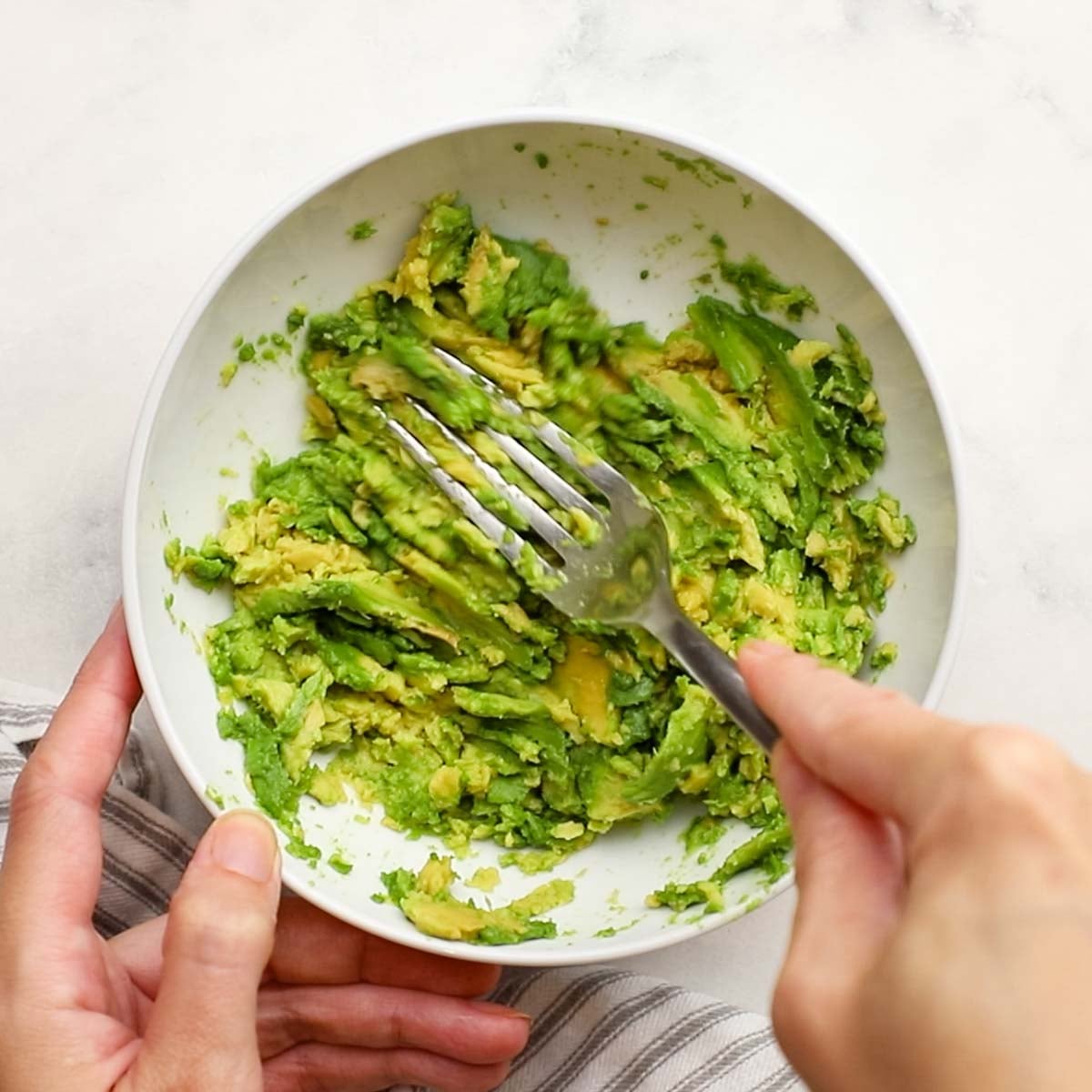 mashing avocado in a bowl