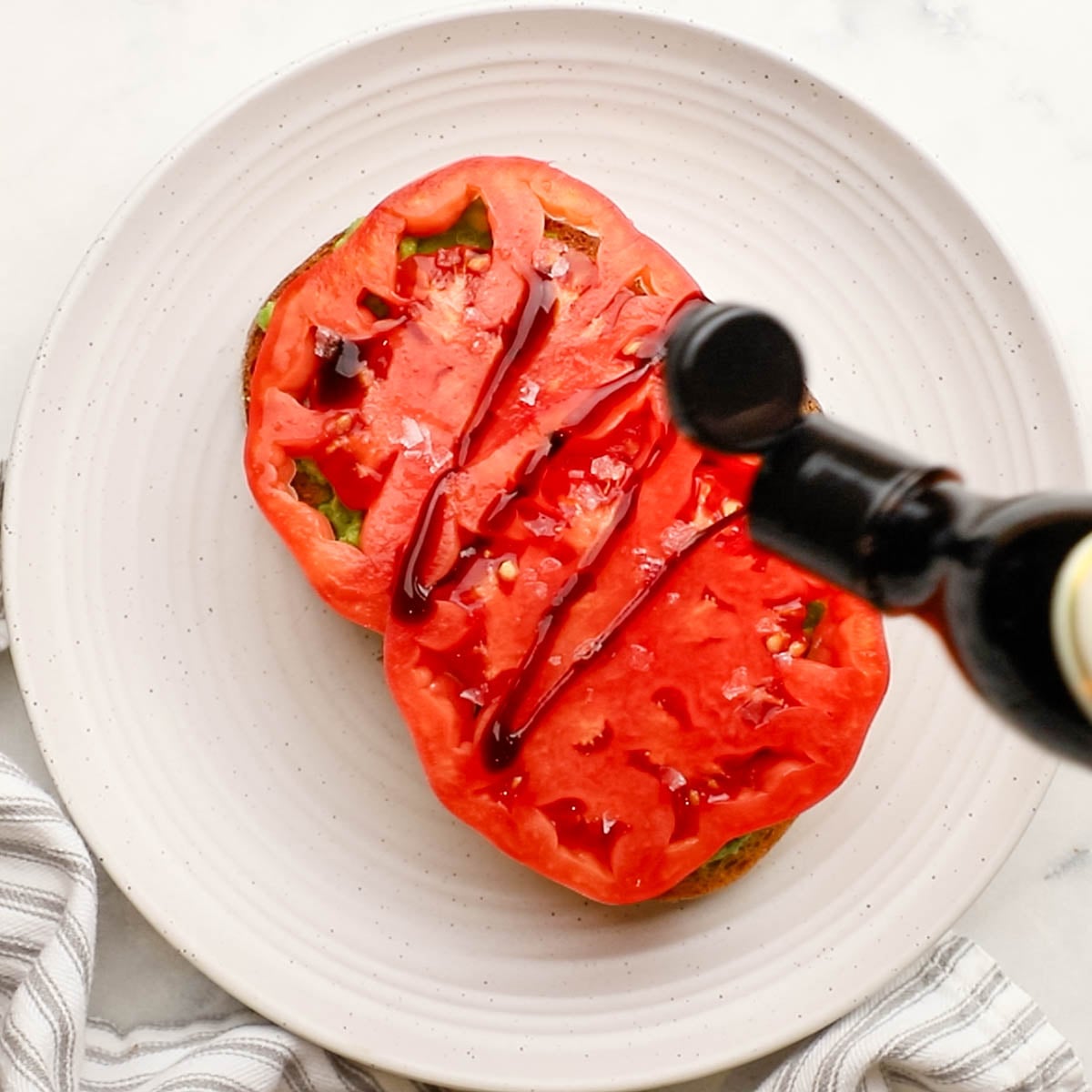 adding balsamic drizzle on tomatoes