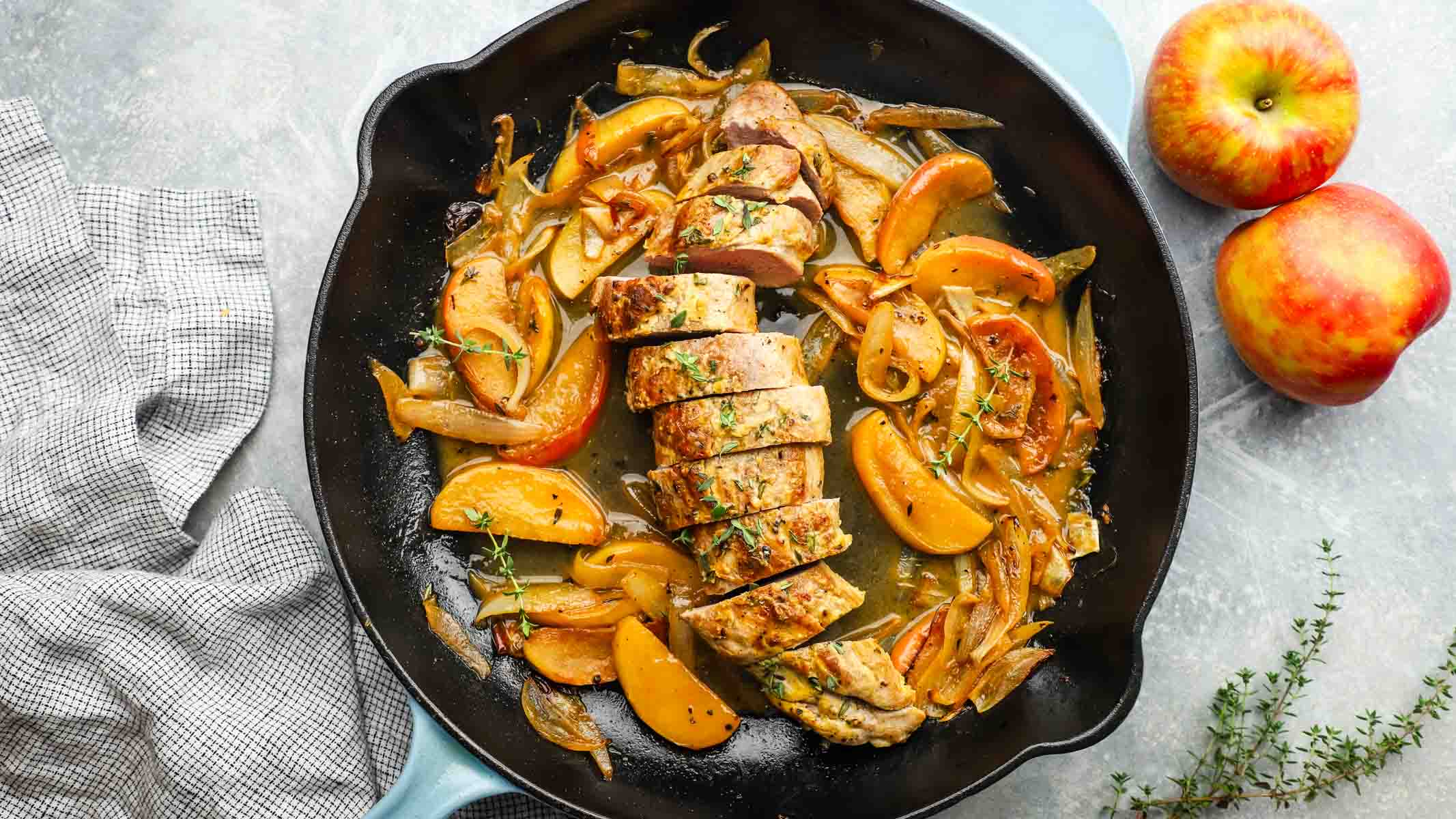a skillet of pork tenderloin with apples and onions.