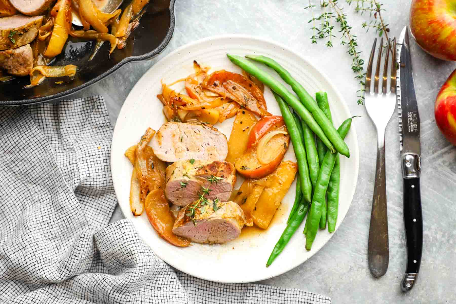 a plate served with pork tenderloin with apples and onions