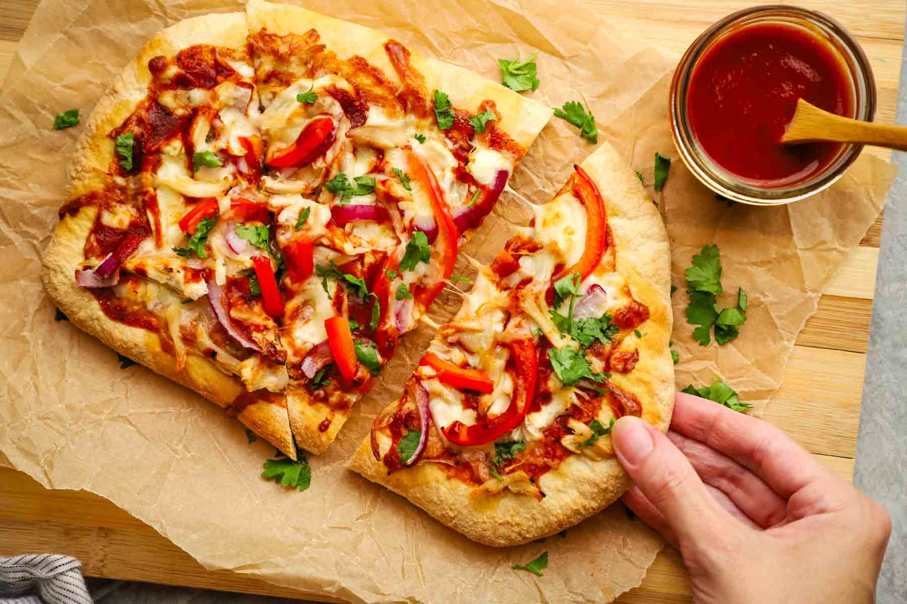 a hand taking out a slice of bbq chicken flatbread