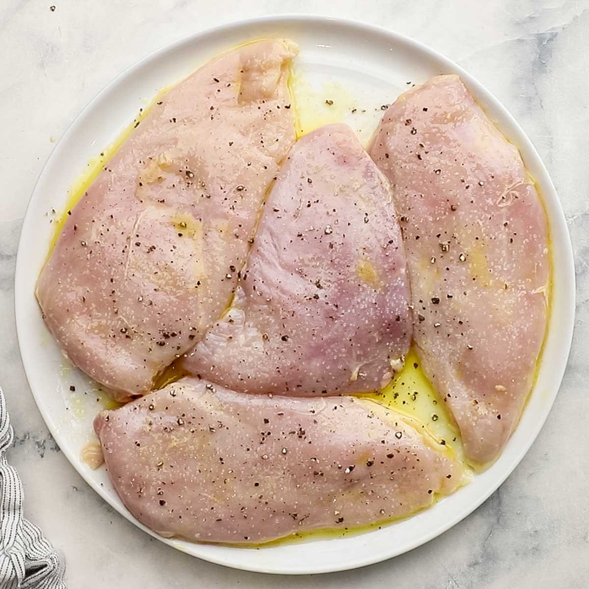 marinated chicken on a plate seasoned with salt and pepper