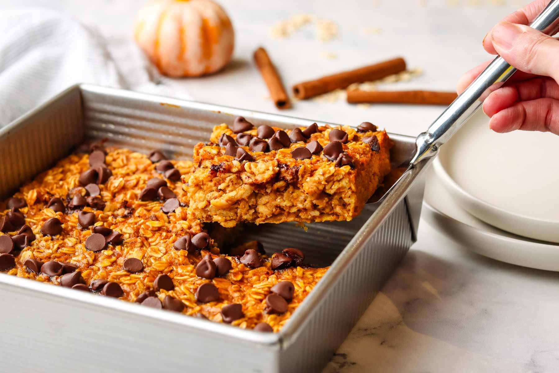 taking out a slice of pumpkin bakd oatmeal from baking dish