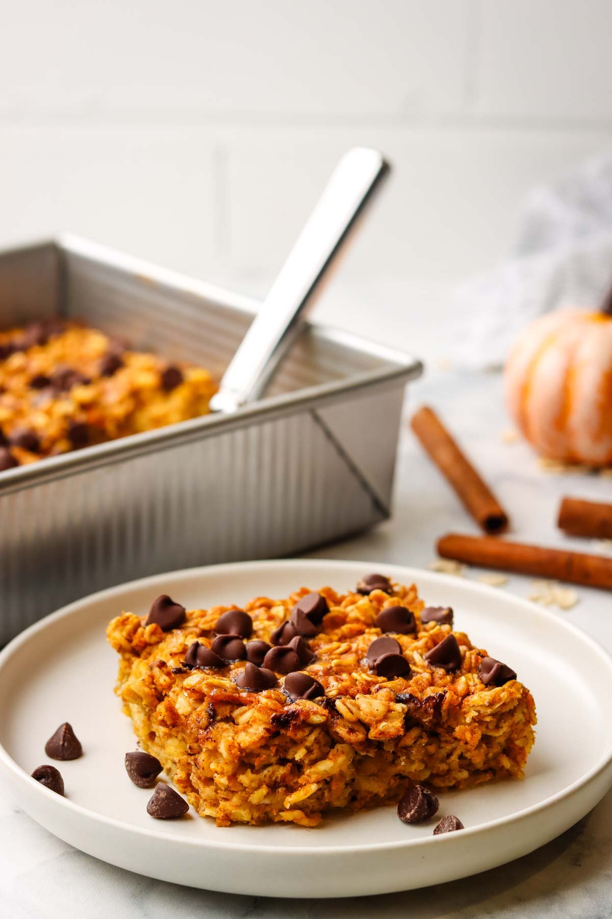 a slice of pumpkin baked oatmeal topped with chocolate chips on a plate.