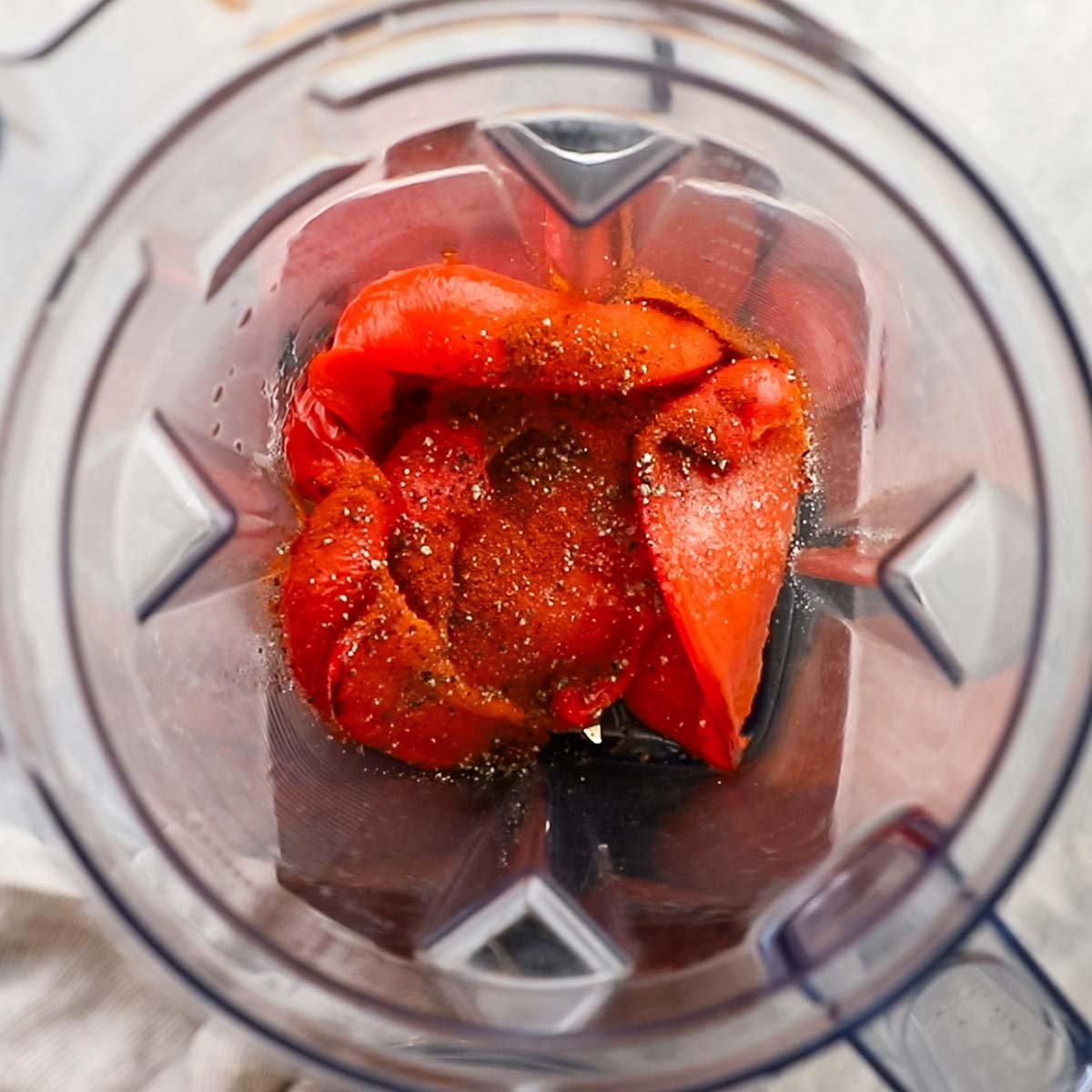 peeled roasted red bell peppers added to a blender with spices and seasonings