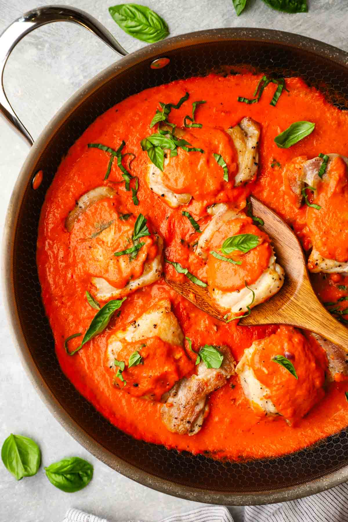 a pan with chicken thighs in a roasted red pepper sauce
