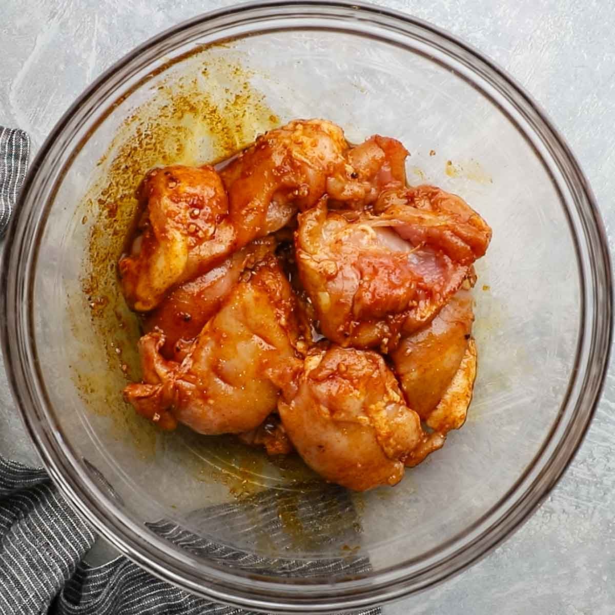 chicken thighs added to the bowl with seasonings