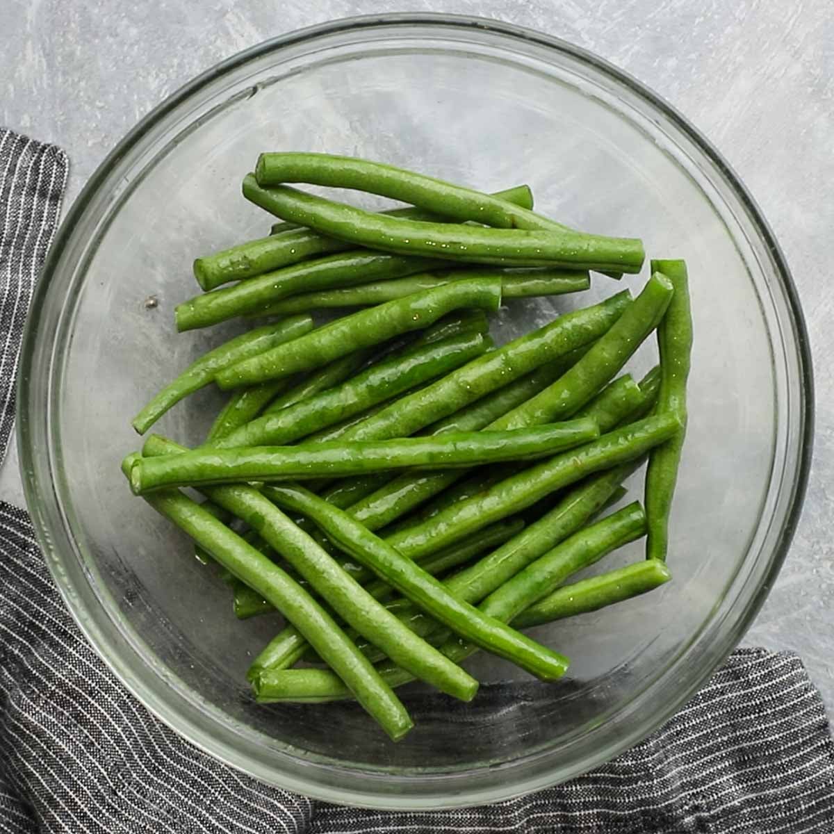 green beans tossed with olive oil in a bowl