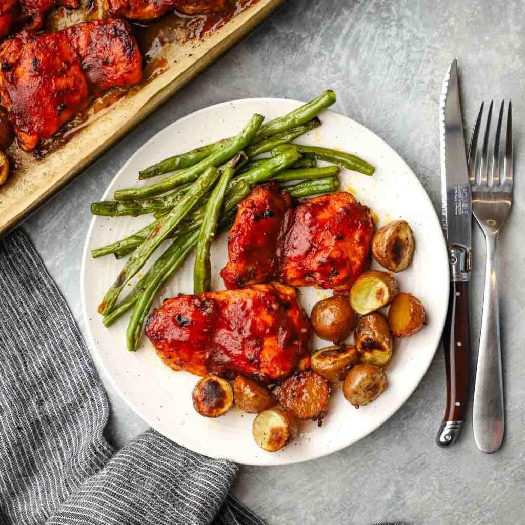 a plate served with bbq chicken, potatoes, and green beans.
