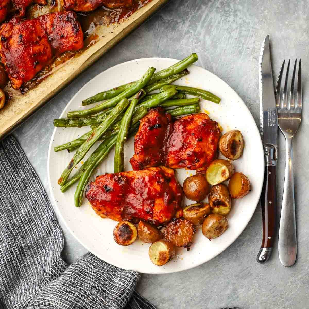 a plate served with bbq chicken, potatoes, and green beans.