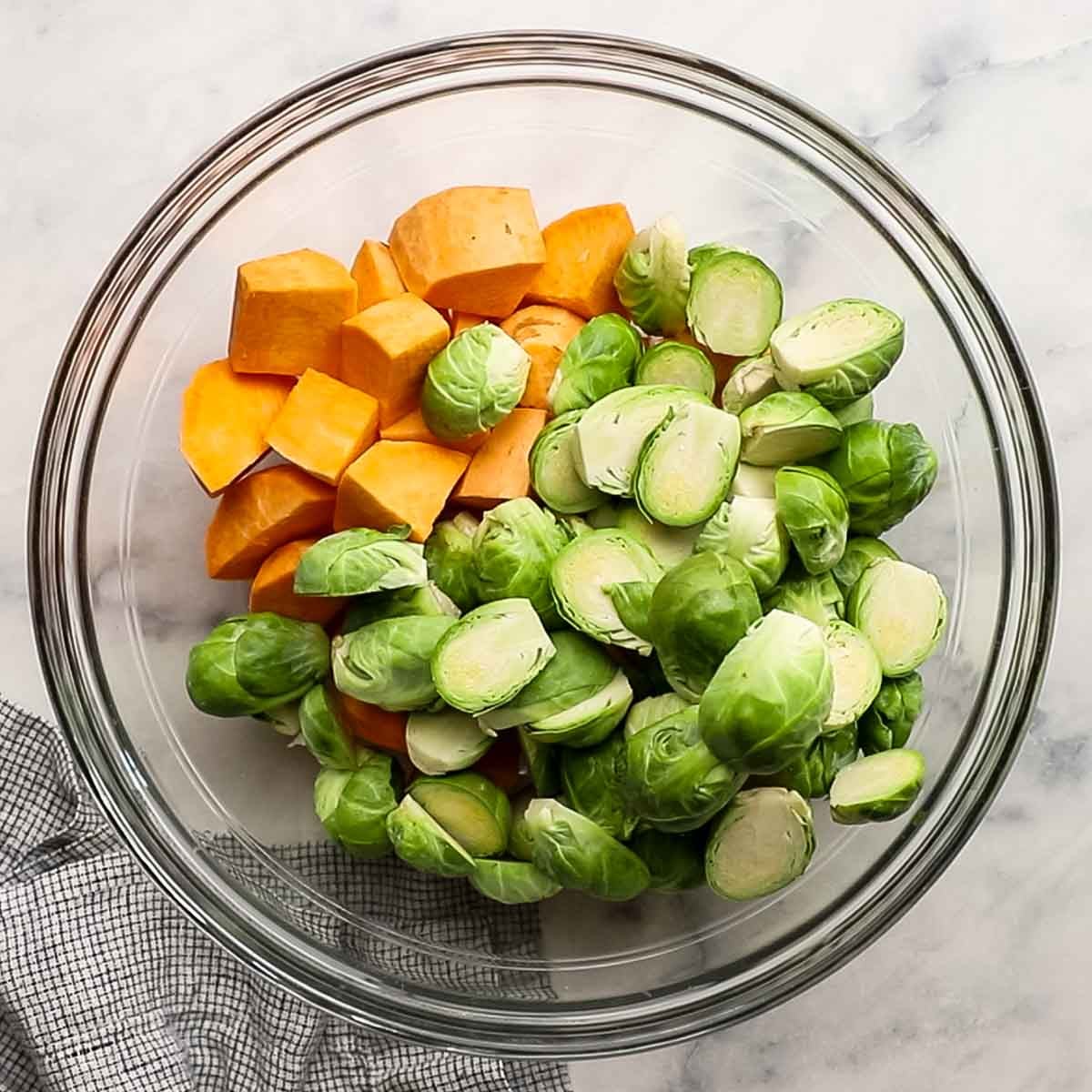 cut up Brussels sprouts and sweet potatoes added to a large bowl