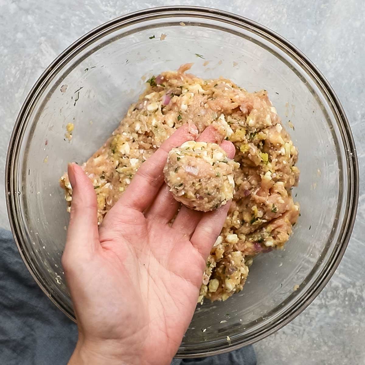 a hand holding a shaped meatballs