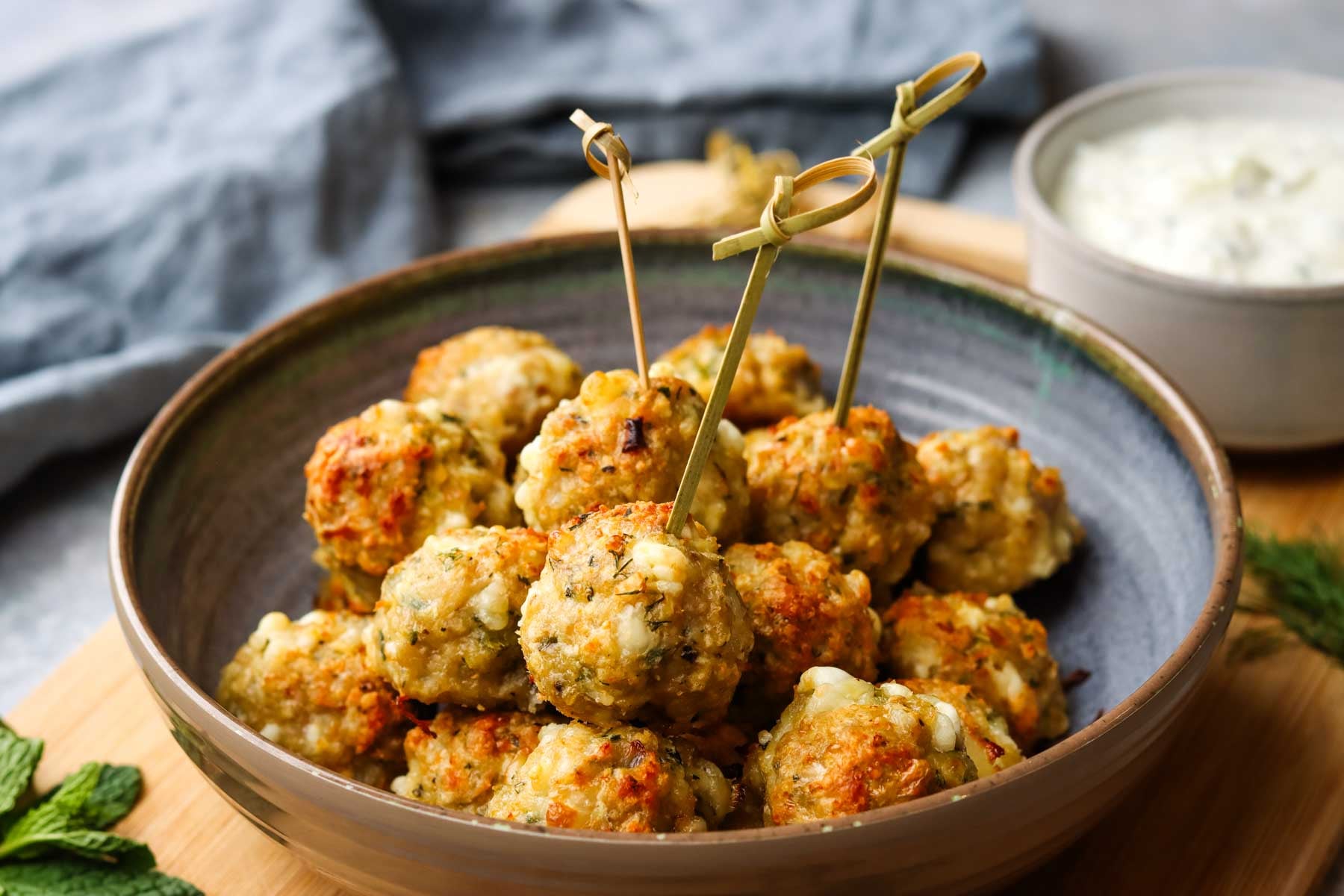 a bowl of chicken feta meatballs with toothpicks inserted in a few