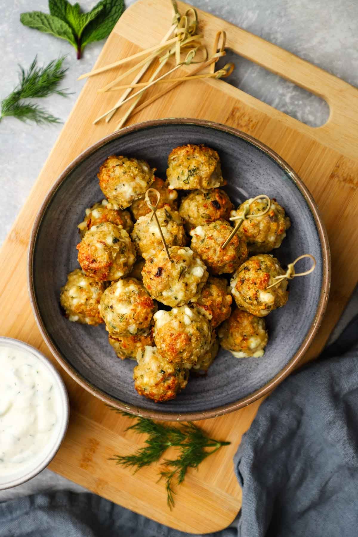 overhead view of a bowl of chicken feta meatballs with toothpicks in it