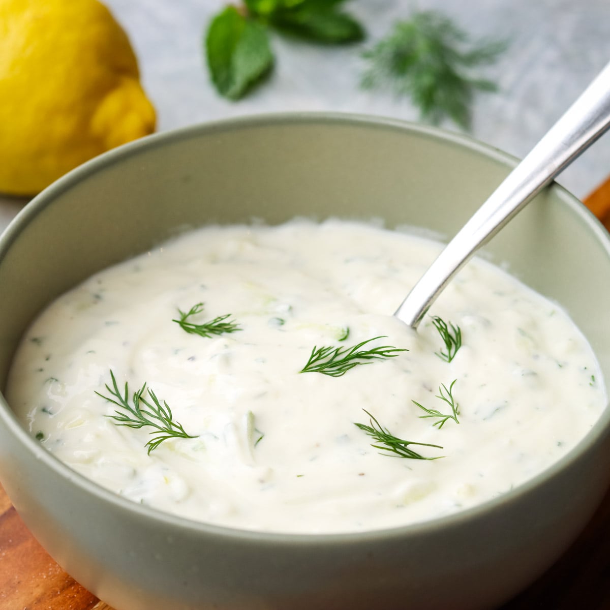 a bowl of cucumber yogurt dip with a spoon in it