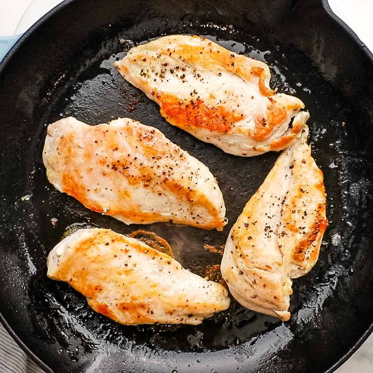 Cooked chicken breasts in a pan.