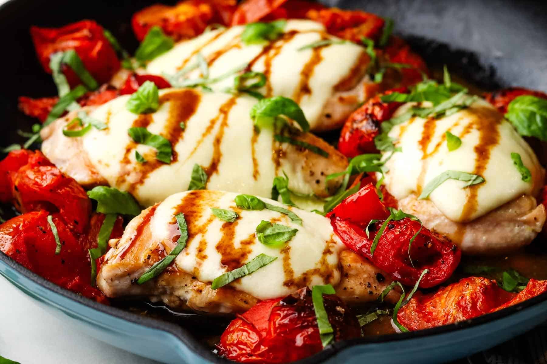 A pan of caprese chicken with roasted tomatoes.