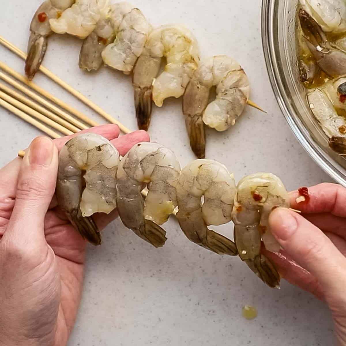 threading the marinated shrimp on wooden skewers