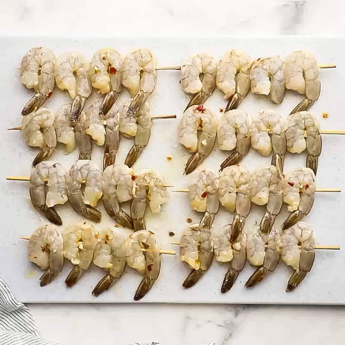 shrimp skewers placed on a cutting board sprinkled with salt